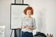 © Westend61 - Smiling businesswoman leading a presentation at flip chart in conference room
