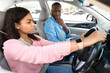 © Prostock-studio - Driving school concept. Scared male course instructor guy looking at serious focused black lady, first time driver sitting inside car watching road, woman having exam for license at training school
