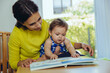 © Westend61 - Mother and baby daughter looking at children?s book