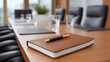 © Thares2020 - A brown notebook and pen rest on a conference table in an executive meeting room
