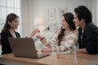 © surachetkhamsuk - Estate agent hands house keys to the client. Asian woman realtor gives keys to the couple buyer while sitting at a table with a house model. Real estate