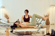 © bnenin - Pilates Class: Instructor Assists Client During Reformers Workout in Modern Wellness Studio