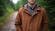© Thares2020 - A man dressed in a stylish brown hooded jacket over a grey shirt walks along a quiet path in a green overcast forest environment