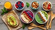 © Md. Rakibul - Flat lay of colorful plant based breakfast with avocado toast, smoothie bowl, berries and nuts on rustic wood, highlighting vegan food, healthy brunch and nutrient rich meals.
