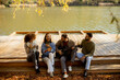 © BGStock72 - Friends enjoying drinks and music by the serene lakeside during a sunny afternoon