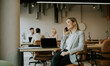 © BGStock72 - Businesswoman on phone in modern coworking space during a busy workday