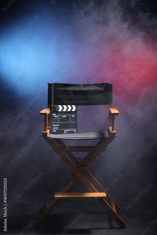 Film director's chair and clapperboard on dark background in neon lights with smoke