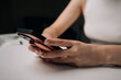 © dikushin - Close-up of woman holding sleek smartphone, featuring trendy protective case with hand strap, providing secure hold and contemporary style. Concept of modern technology and stylish accessories.