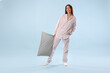© New Africa - Beautiful woman in stylish pajamas with pillow on light blue background
