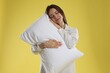 © New Africa - Beautiful woman in stylish pajamas with pillow on yellow background