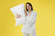© New Africa - Beautiful woman in stylish pajamas with pillow on yellow background