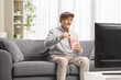 © Ljupco Smokovski - Senior man on a couch watching tv and eating popcorn