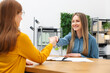 © New Africa - Smiling recruiter and candidate shaking hands at table in office