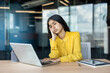 © Tetiana - Tired young Indian businesswoman sitting in the office, holding her head and looking sadly at the laptop screen