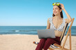 © New Africa - Happy woman in top of swimsuit, office pants and diving mask holding laptop in deck chair at beach. Time for vacation
