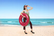 © New Africa - Happy woman in top of swimsuit, office pants and high heels holding inflatable ring at beach. Time for vacation