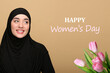 © New Africa - Happy Women's day celebration. Smiling muslim woman in hijab and bouquet of tulips on dark beige background