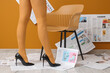 © Pixel-Shot - Legs of woman in high heels with many newspapers near chair against orange wall, closeup