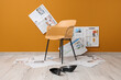 © Pixel-Shot - Chair with high heels and many newspapers near orange wall in room