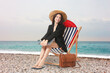 © New Africa - Businesswoman with laptop sitting in deck chair at beach. Time for vacation