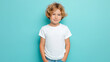 © Jackpot - A young boy with curly hair stands confidently in front of a solid teal background wearing a white t-shirt.