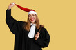 © Pixel-Shot - Young female judge in Santa hat on yellow background