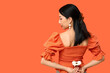© Pixel-Shot - Young Asian woman with white gerbera flower on orange background