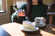 © Farknot Architect - Closeup image of a woman eating a piece of coconut cake and drinking hot chocolate in cafe