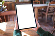 © Farknot Architect - Mockup image of a woman holding digital tablet with blank white desktop screen in cafe