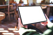 © Farknot Architect - Mockup image of a woman holding digital tablet with blank white desktop screen in cafe