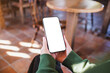 © Farknot Architect - Mockup image of a woman holding and using mobile phone with blank desktop screen in cafe