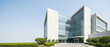 © Hamy - Contemporary glass office building or hospital research center architecture against blue sky, corner view with landscaping.