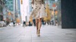 © ON - Studio - Person walking on a city sidewalk in a beige trench coat. Urban lifestyle and fashion concept with blurred background. Low angle perspective