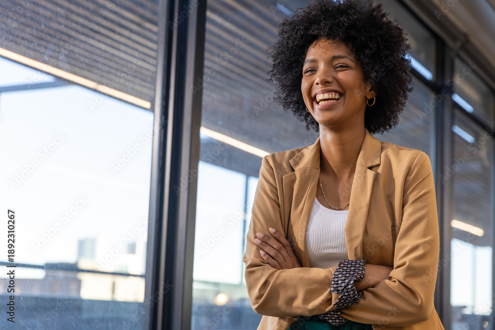 African american woman smiling by windows in office wearing blazer ...