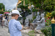 © creativefamily - Young Boy Using Toy Camera to Photograph Statues in Lush Garden Setting in Bangkok, Thailand