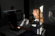 © Maskot - Blond female tech expert working at desk in dark office