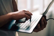 © Maskot - Hand of businessman holding smart phone while pressing laptop key