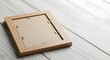 © antuanetto - A light wooden photo frame lying face down on a clean white table, illustrating a minimalist home decor concept or a blank canvas for new memories