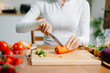 © Nuttapong punna - Close up of woman cutting fresh carrot in home kitchen. Healthy cooking, clean eating, nutrition, meal prep and vegetarian lifestyle with organic ingredients.