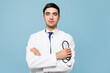 © ViDi Studio - Young confident male doctor man wear white medical gown suit work in hospital clinic office hold in hand use stethoscope isolated on plain blue background studio portrait. Healthcare medicine concept.