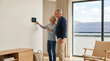 © Art_spiral - Senior couple using smart thermostat in modern minimalist home with solar panels outside sustainable energy efficient living smart home technology and retirement lifestyle