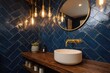 © KAHAR - A modern bathroom features a round mirror, brass fixtures, a wooden counter, and a stunning blue tiled wall. Soft light emanates from hanging bulbs