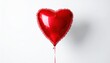 © danastri - A single shiny red heart shaped balloon floating against a clean white background.