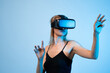 © Volodymyr_sh - Female user interacting with virtual environment using hand gestures in VR headset, immersive digital technology concept