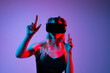 © Volodymyr_sh - Female gamer adjusting VR headset while playing virtual reality game in neon red blue lighting studio environment