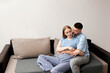 © verona_studio - Couple sitting together on a sofa, enjoying each others company in a cozy indoor setting during the afternoon