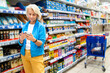 © Alfonso Soler - Senior woman using smartphone shopping in supermarket