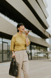 © BGStock72 - Cheerful woman walking outside an office building while talking on her phone