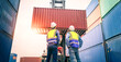 © nuttawutnuy - Two Engineer or foreman wears PPE checking container storage with cargo container background at sunset. Logistics global import or export shipping industrial concept.