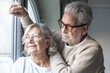 © luciano - Relaxed  bonding old senior retired couple standing near the window, looking in distance, recollecting good memories or planning common future, enjoying peaceful moment together at home